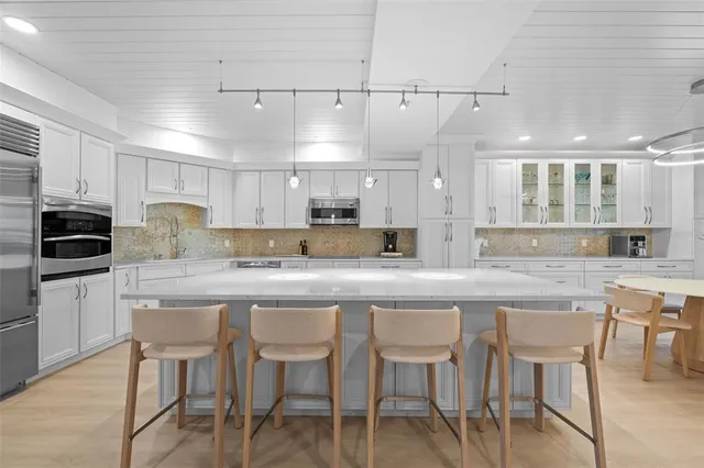 a kitchen with stainless steel appliances granite countertop a table chairs sink and cabinets