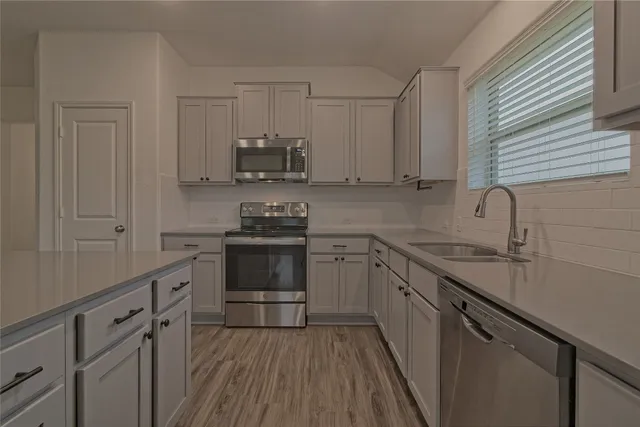 an empty room with wooden floor chandelier and windows