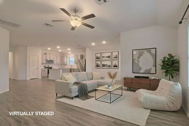 an empty room with wooden floor a ceiling fan and windows