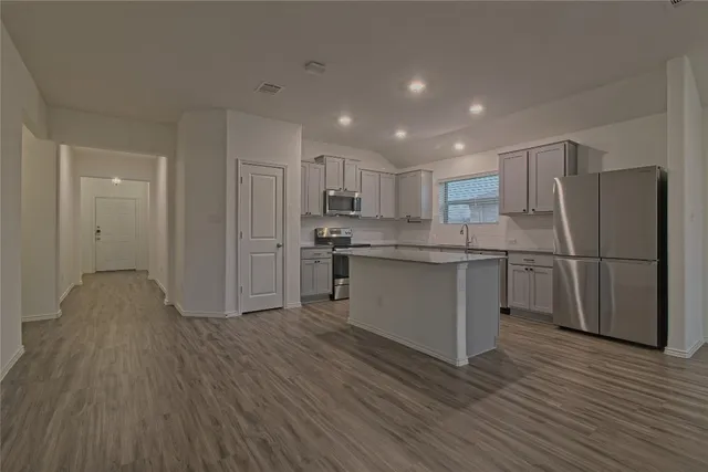 a kitchen with stainless steel appliances granite countertop a refrigerator sink and white cabinets