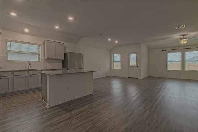 a kitchen with granite countertop a stove a sink and white cabinets with wooden floor