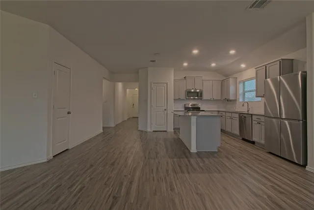 a kitchen with a refrigerator and wooden floor