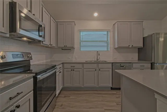 a kitchen with stainless steel appliances granite countertop a sink stove microwave and refrigerator