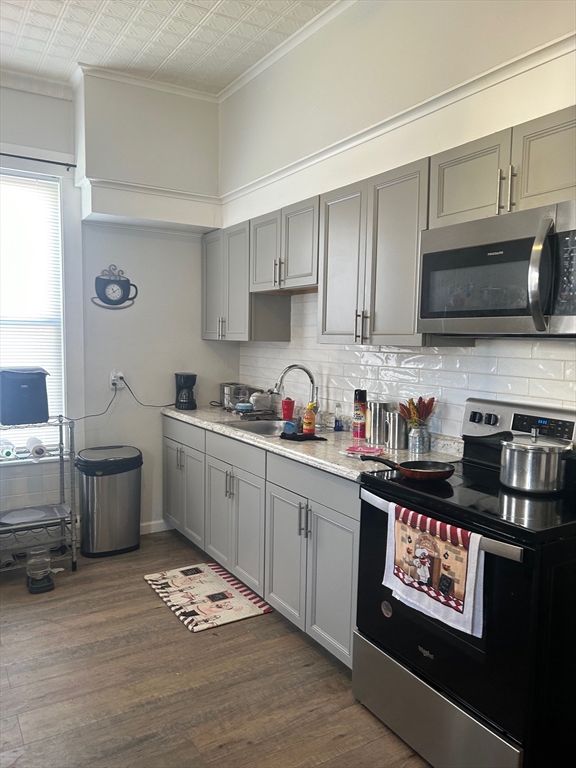 237 Branch Street Lowell, MA 01851 - Photo 12 of 15 a kitchen with stainless steel appliances kitchen island granite countertop a refrigerator stove top oven and sink with wooden floor