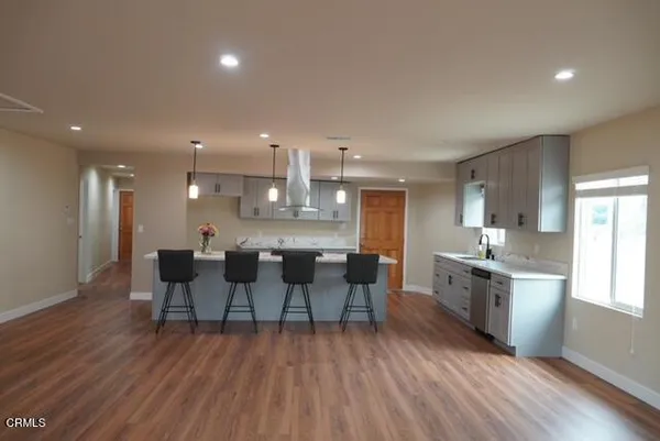 a kitchen with a dining table chairs wooden floor appliances and cabinets