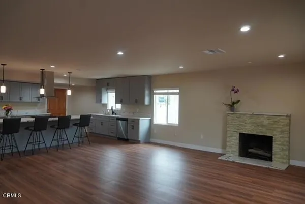 an empty room with wooden floor fireplace and windows