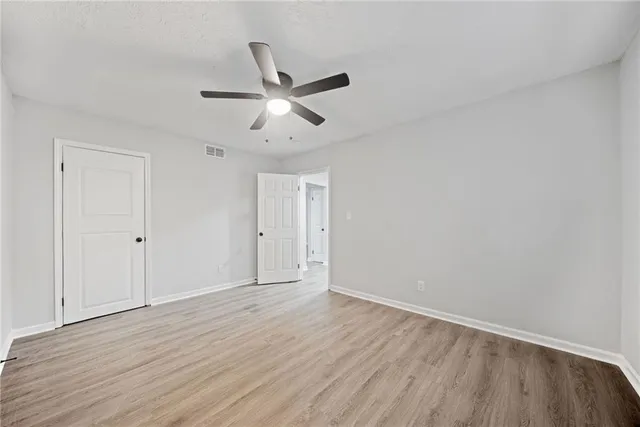 an empty room with wooden floor and ceiling fan