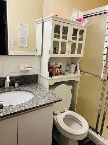 a bathroom with a granite countertop toilet sink and mirror