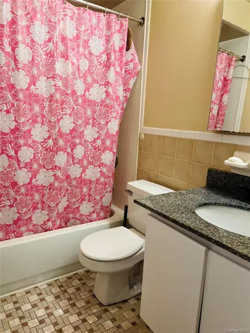 a bathroom with a granite countertop toilet sink and mirror