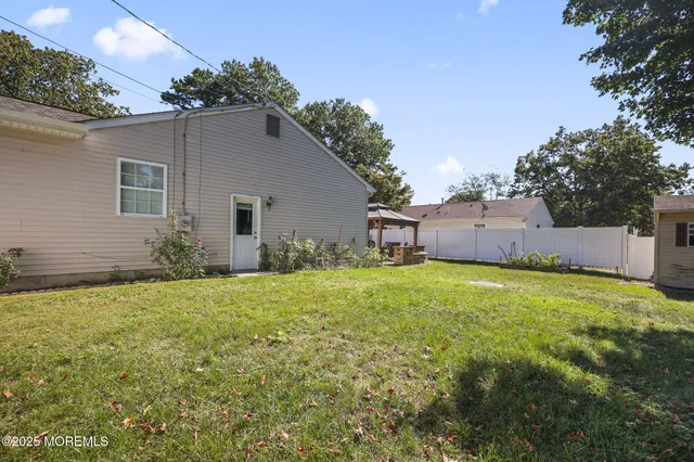 a backyard of a house with table and chairs plants and large tree