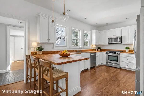 a kitchen with stainless steel appliances a stove a sink dishwasher a refrigerator with a dining table and chairs