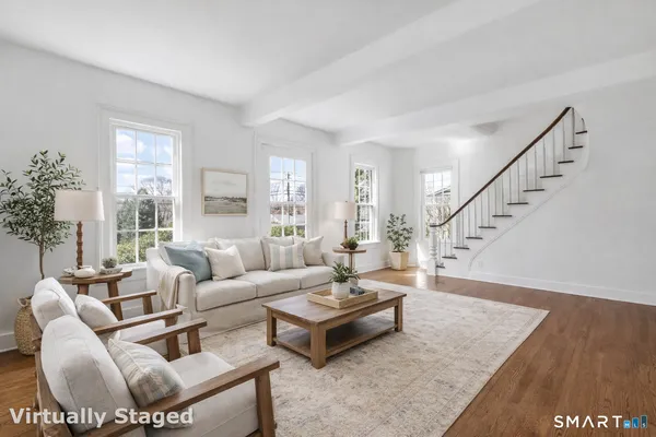 a living room with furniture and a dining table with wooden floor