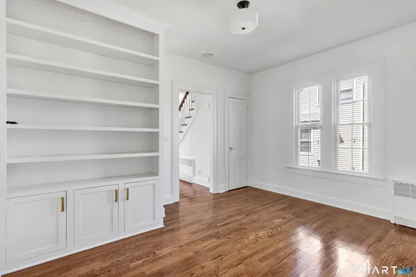 a view of an empty room with a window and wooden floor