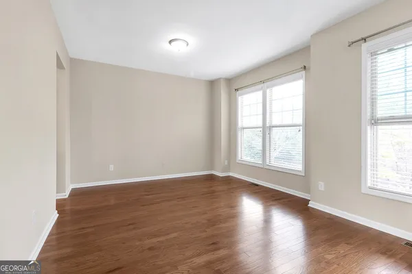 an empty room with wooden floor and windows