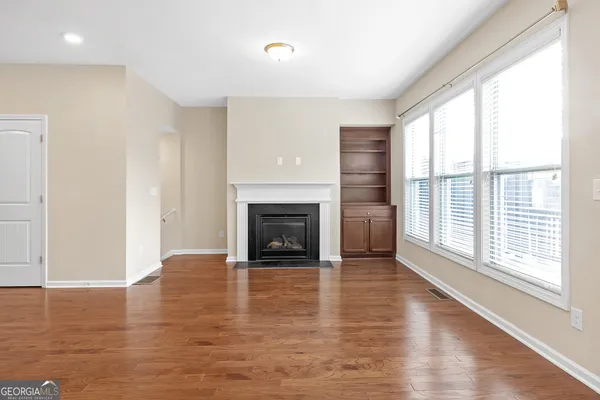 a view of an empty room with wooden floor and a window