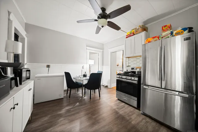 a kitchen with stainless steel appliances a refrigerator a sink dishwasher a stove and white cabinets with wooden floor