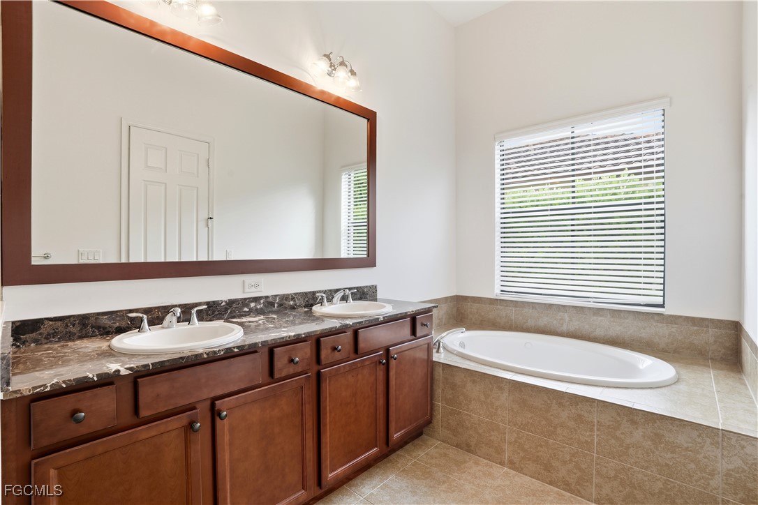 5355 Ferrari Avenue Ave Maria, FL 34142 - Photo 15 of 28 a bathroom with a granite countertop sink a mirror and a bathtub