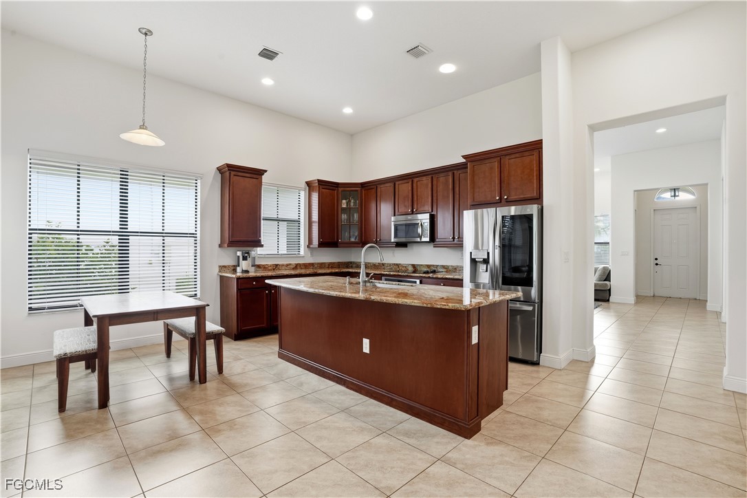 5355 Ferrari Avenue Ave Maria, FL 34142 - Photo 7 of 28 a large kitchen with stainless steel appliances wooden cabinets a center island a stove a refrigerator and a view of living room