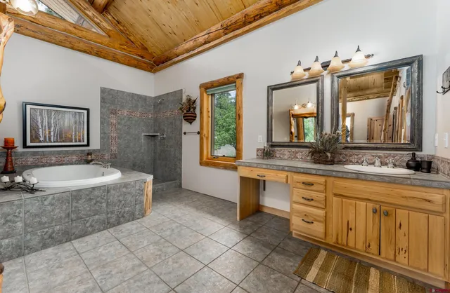 a spacious bathroom with a granite countertop sink a mirror a bathtub and a shower