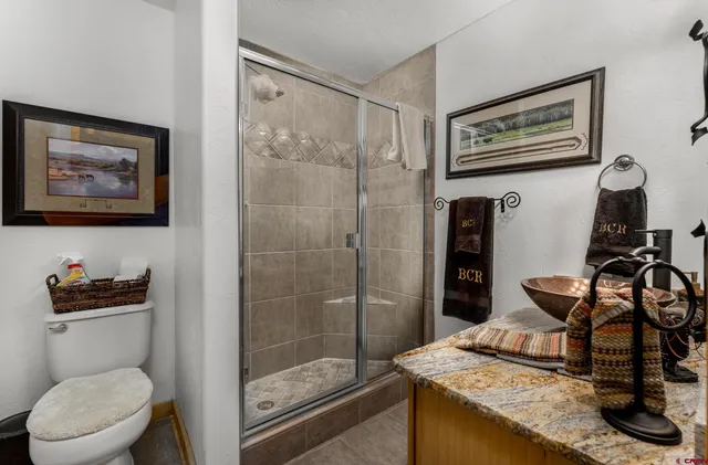 a bathroom with a granite countertop sink a toilet and a shower