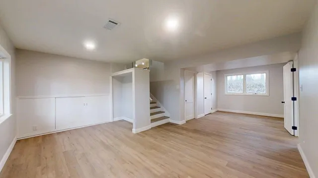 an empty room with wooden floor and windows