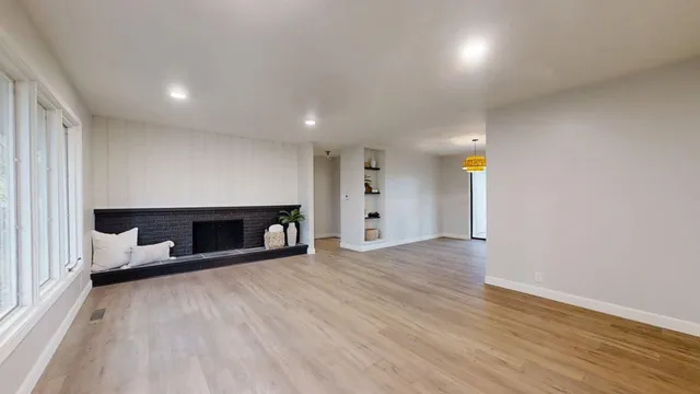 a view of an empty room with a fireplace and a window