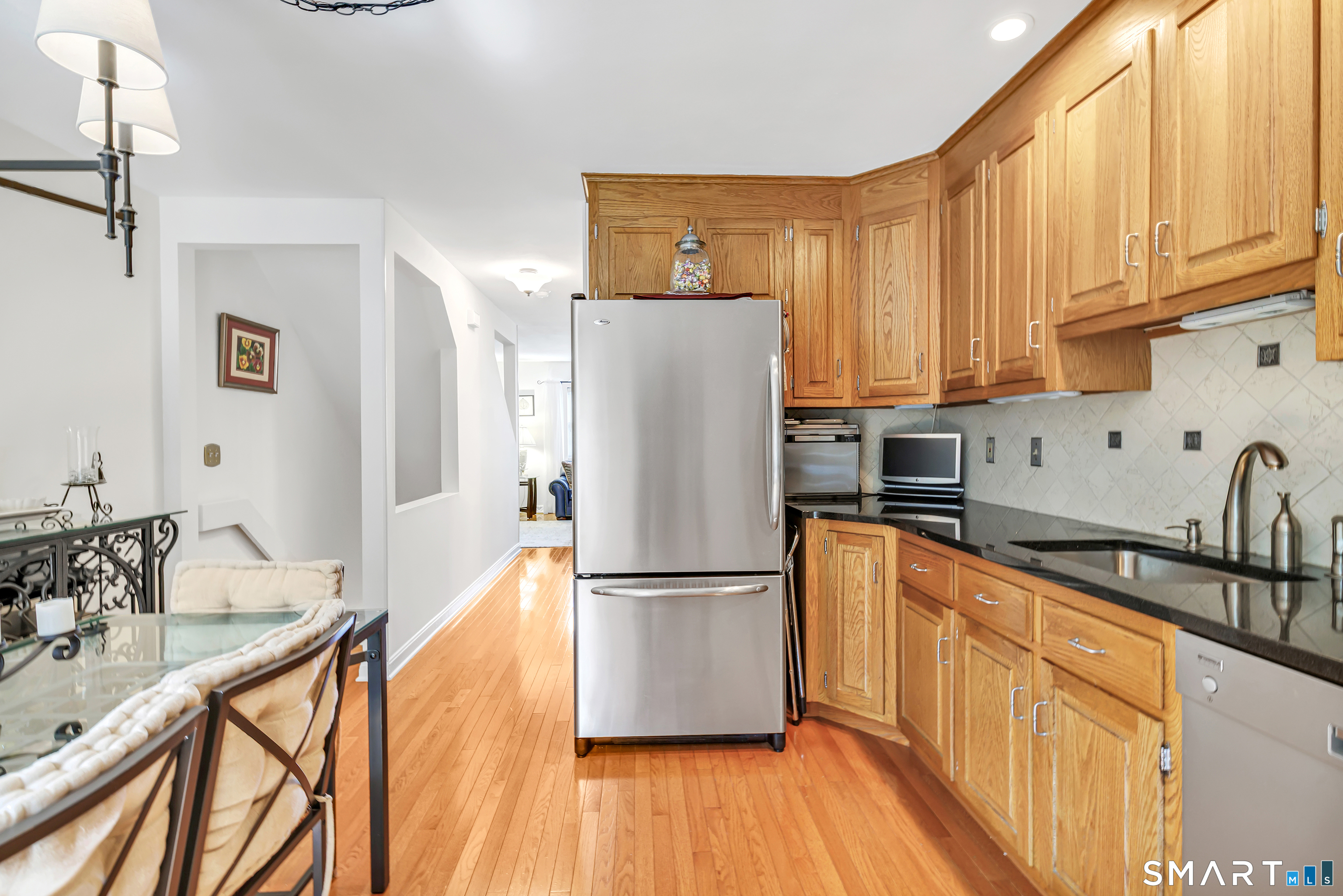 146 Howe Avenue, Unit 146 Shelton, CT 06484 - Photo 9 of 35 a kitchen with stainless steel appliances granite countertop a refrigerator a sink dishwasher and wooden cabinets with wooden floor