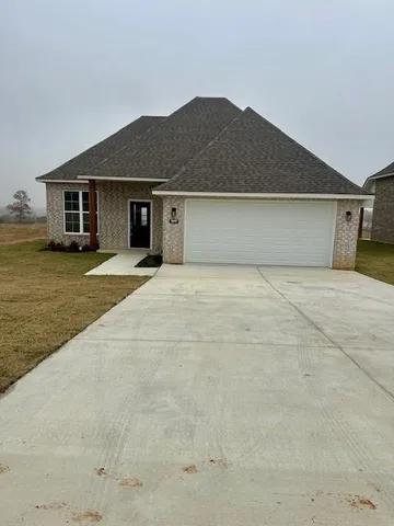 a front view of house with yard and trees in the background