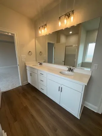 a spacious bathroom with a double vanity sink a mirror and a shower