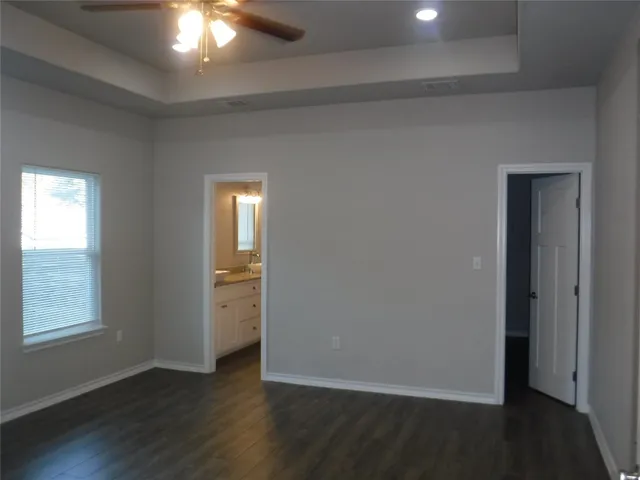 an empty room with wooden floor closet and windows