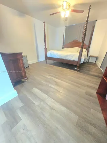 a bedroom with wooden floor and a ceiling fan