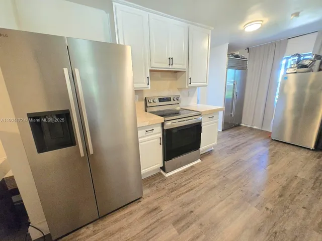 a kitchen with stainless steel appliances a refrigerator a sink a stove a microwave and wooden floors