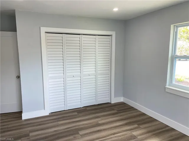 an empty room with wooden floor and windows with curtains