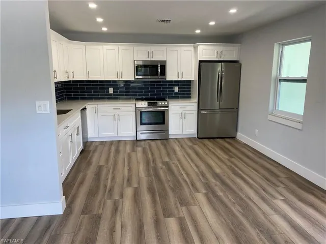a kitchen with kitchen island granite countertop white cabinets and stainless steel appliances