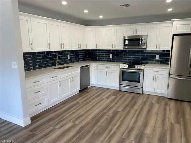 a kitchen with granite countertop white cabinets and stainless steel appliances