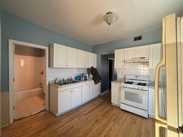a kitchen with a sink wooden floor and stainless steel appliances