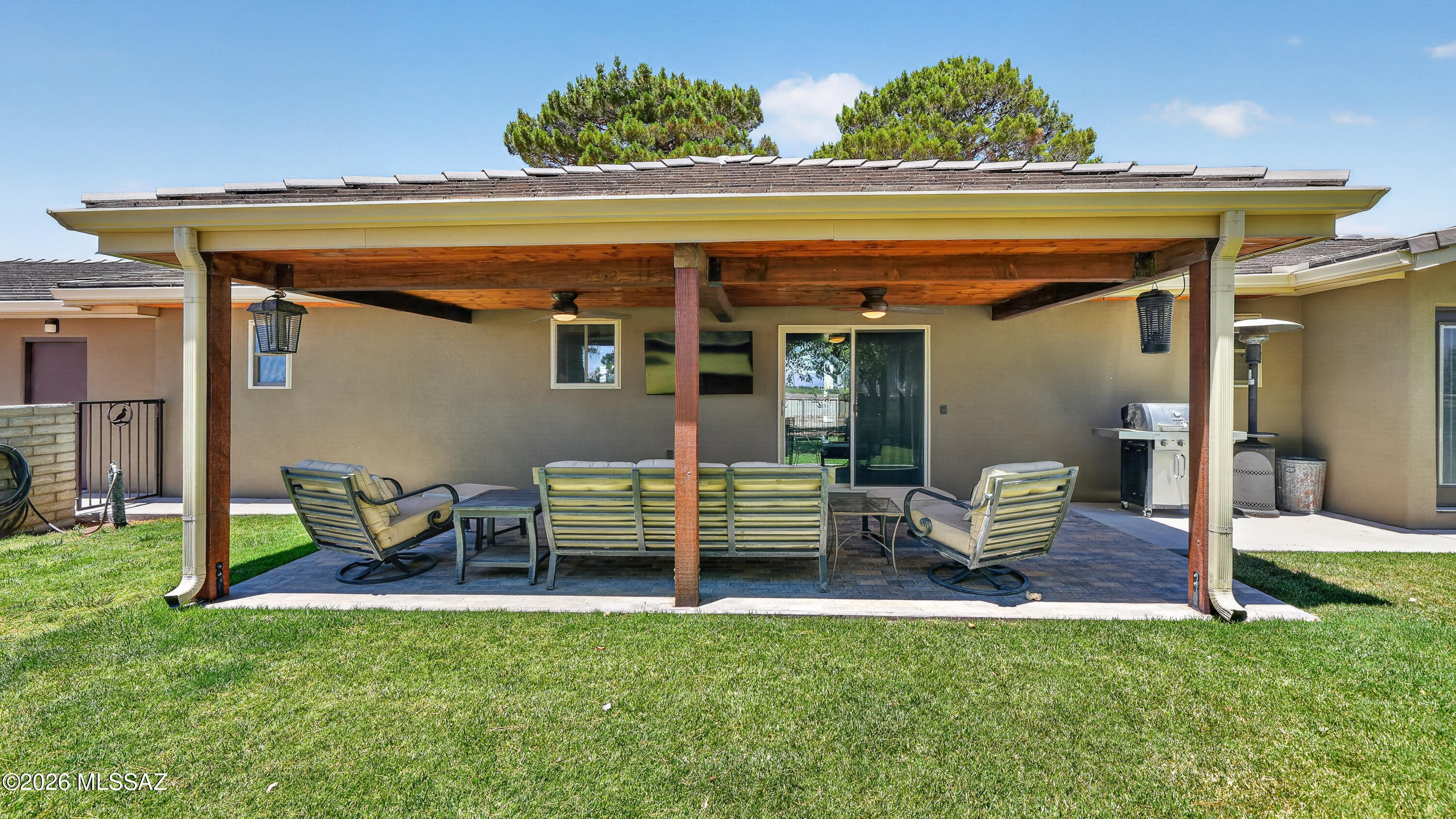 194 Taylor Road Willcox, AZ 85643 - Photo 35 of 54 Spacious covered back patio with rough-sawn tongue-and-groove wood ceilings, tiled flooring, outdoor ceiling fans, and a TV setup. The backyard features grass, automatic in-ground sprinklers, three fruit trees, two cypress trees, and raised garden/flower beds. House faced West so you do not get the Evening Sun, Perfect for dinning outside and watching your favorite shows outside
