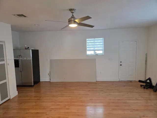 a view of an empty room with a window and a kitchen