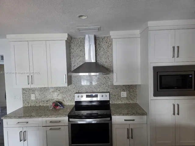 a kitchen with stainless steel appliances granite countertop a stove a microwave and a white cabinets