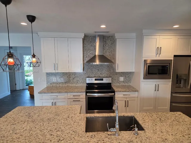 a kitchen with stainless steel appliances granite countertop a stove a sink and a microwave