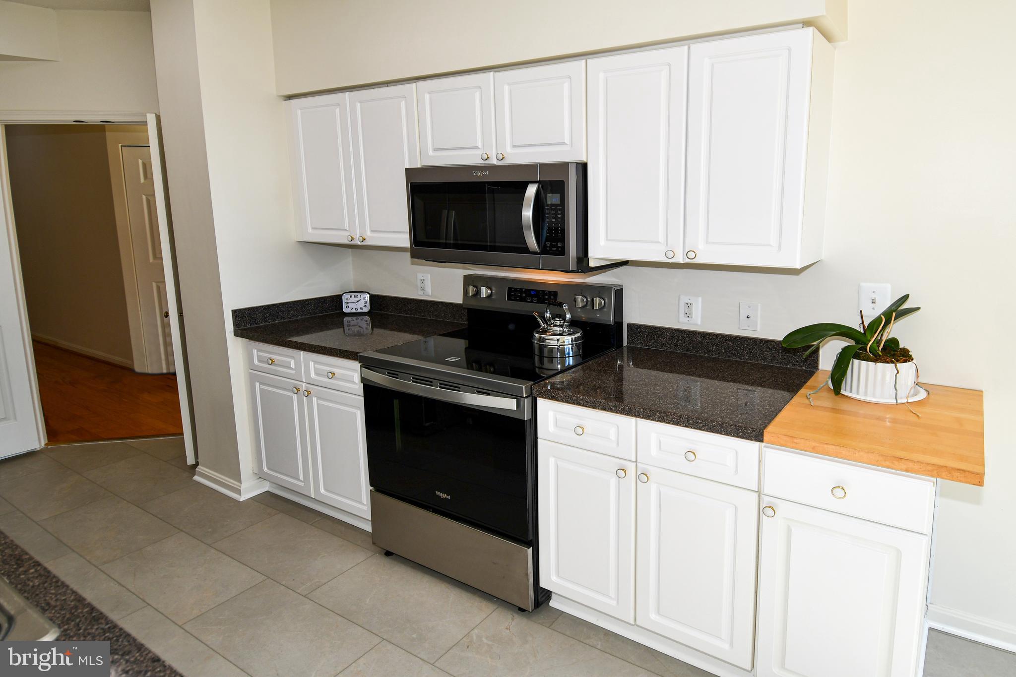 3100 North Leisure World Boulevard, Unit 801 Silver Spring, MD 20906 - Photo 23 of 69 a kitchen with white cabinets and a stove with wooden floor