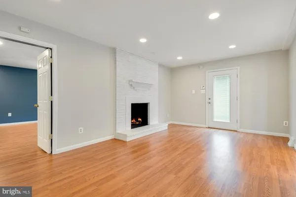 a view of an empty room with wooden floor and a fireplace