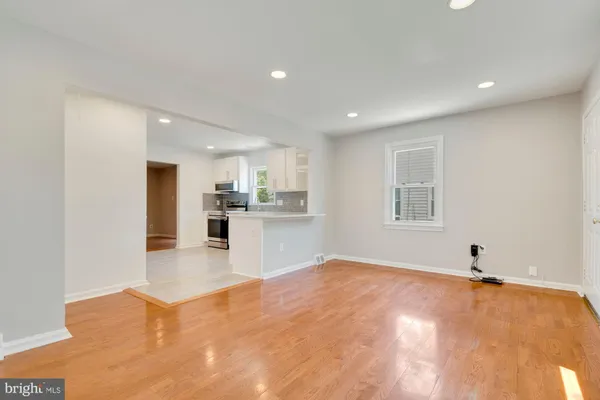 a view of an empty room with kitchen and window