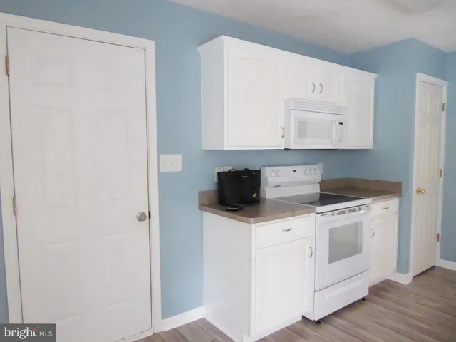 a kitchen with stainless steel appliances granite countertop white cabinets and a stove top oven