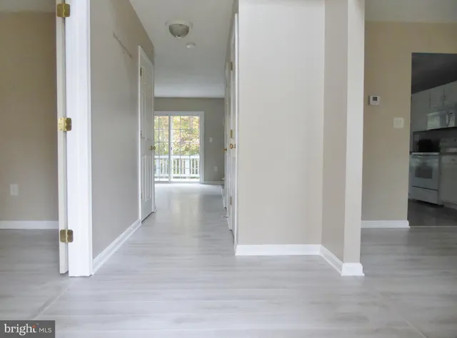 a view of a hallway with wooden floor and a bathroom