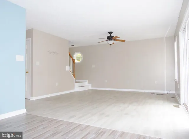 a view of a room with wooden floor and a ceiling fan