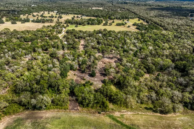 an aerial view of residential house with outdoor space and trees all around