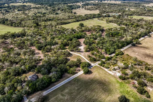 an aerial view of residential houses with outdoor space and trees