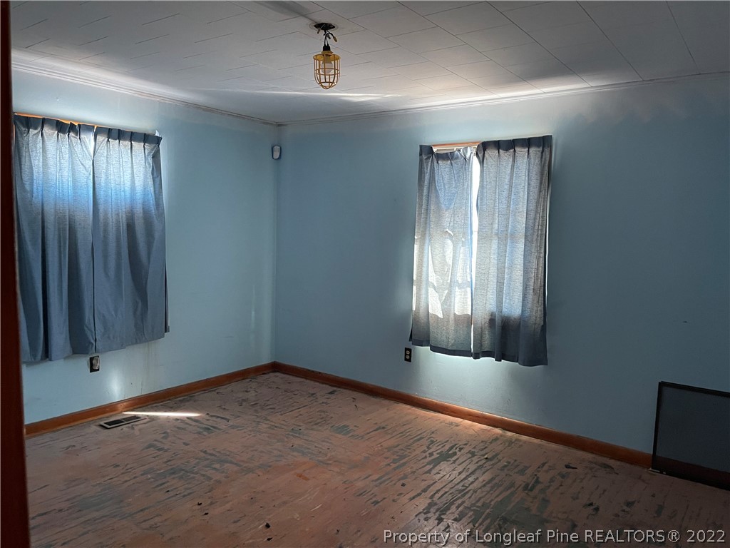 6990 Rockfish Road Fayetteville, NC 28306 - Photo 9 of 12 an empty room with wooden floor and windows