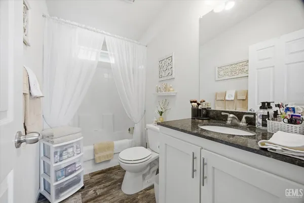 a bathroom with a granite countertop sink mirror vanity and toilet